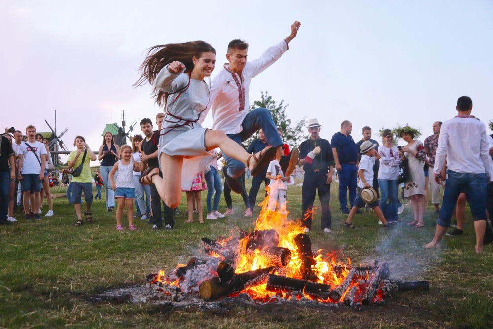 Latvian Jāņi bonfire at night with people wearing oak wreaths